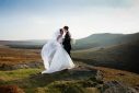 Couple in wedding dress and suit on a hill being snapped by a wedding photographer in Kent